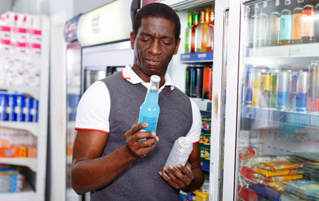Portrait of happy cheerful positive smiling Afro man buying carbonated beverages in store