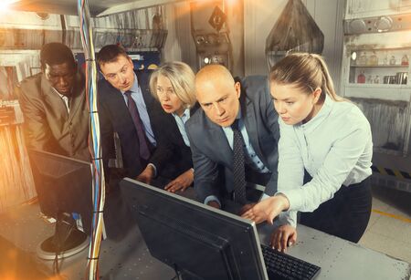 Toned image of businesspeople trying together to find solution of conundrum in quest room  in view as abandoned lab during corporate team buildingの写真素材