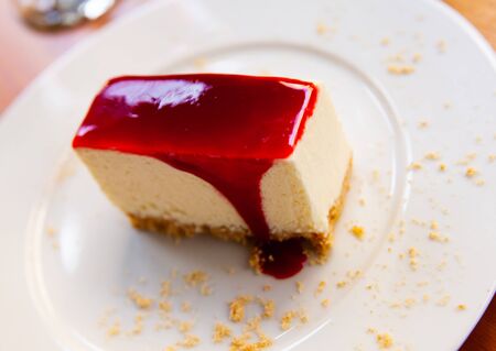 Slice of delicious classical cheesecake with fruity sauce served in cafeteriaの写真素材