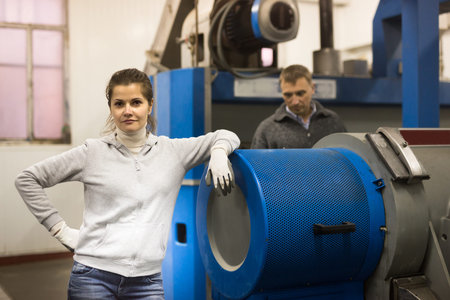 Portrait of confident woman owner of small olive oil factory standing near equipments. Concept of...