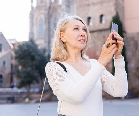 Elegant woman in white blouse makes selfie on smartphone