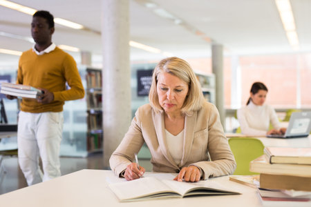 Woman with books sits at table in the library