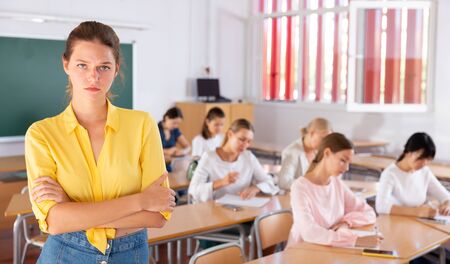 Upset girl standing during classes in auditorium with fellow students on backgroundの写真素材