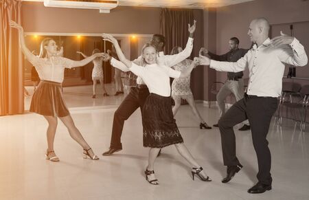 Adult dancing couples enjoying active boogie-woogie in modern studioの写真素材