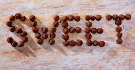 Top view of word Sweet lined with chocolate candies truffles on wooden surfaceの写真素材