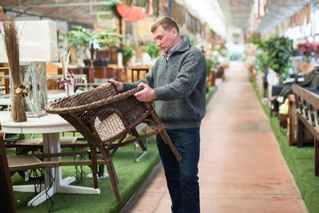 Interested man looking for original wicker armchair in modern furniture salonの写真素材
