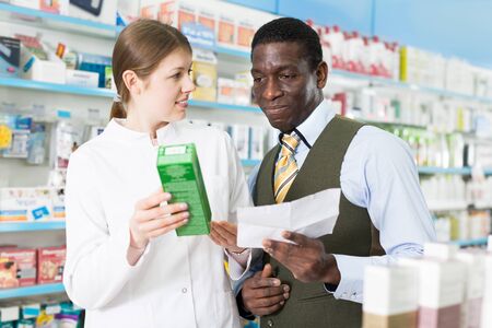 Woman pharmacist talking with man client, picking up prescription medicines  の写真素材