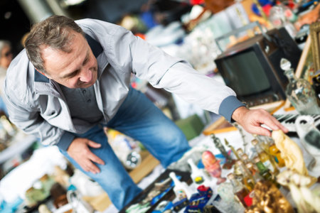 Adult male is visiting the market of old things and shopping outdoors