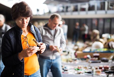 Mature female is visiting the market of old things and choosing casket outdoorsの写真素材
