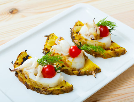 Sepia fried on a grill with pineapple and cherry tomatoes is tasty dish in the kitchen.