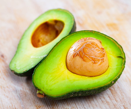 Image of close up of cut avocado with bone at wooden table