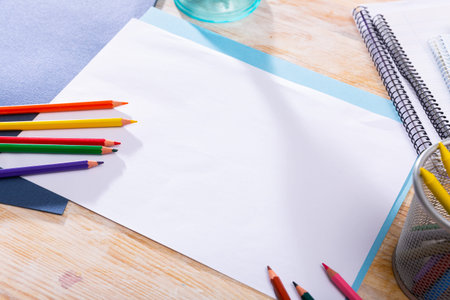 Clean sheet of white paper with color pencils and wax crayons on wooden table. Creativity concept