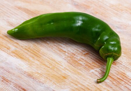 Closeup of one fresh green chili pepper on wooden background. Healthy nutrition conceptの写真素材