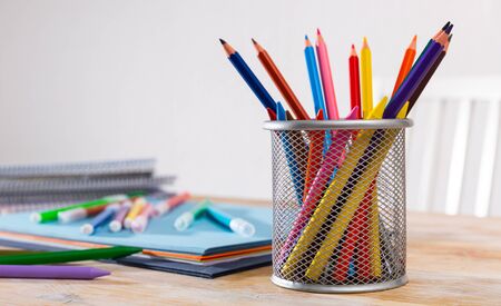 Closeup of pencils and wax pastel with papers and workbooks on desk in light home interior. Concept of artistic education and art の写真素材