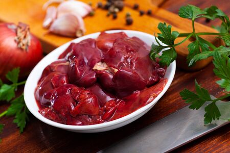 Fresh raw chicken liver in white plate with seasonings on wooden backgroundの写真素材