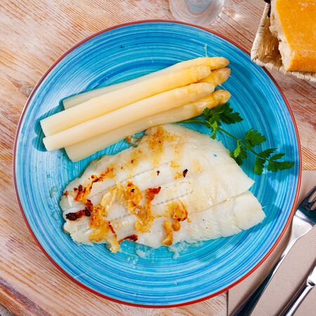 Tasty fried halibut fish fillet with asparagus and greens on plateの写真素材