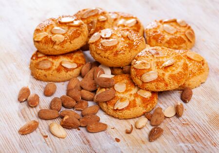 Closeup of crispy macaroons with dried almonds on wooden tableの写真素材