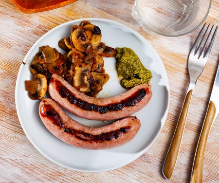 Grilled sausages served with roasted mushrooms with onion and pesto sauceの写真素材