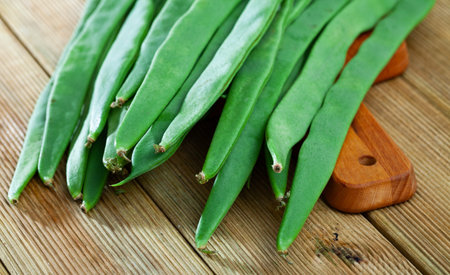 Healthy nutrition concept. Flat pods of raw helda beans on wooden background