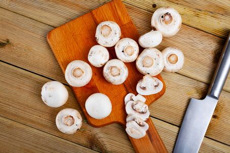 Fresh champignon mushrooms on a wooden cutting boardの写真素材