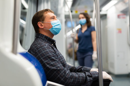 Male passenger in personal protective equipment traveling in subway during the COVID-19 virus...