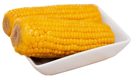 Delicious sweet boiled corn cobs on plate. Healthy food concept. Isolated over white backgroundの写真素材