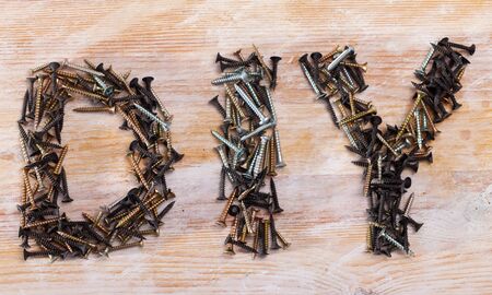 Do It Yourself abbreviation DIY lined with various metal screws on wooden surfaceの写真素材