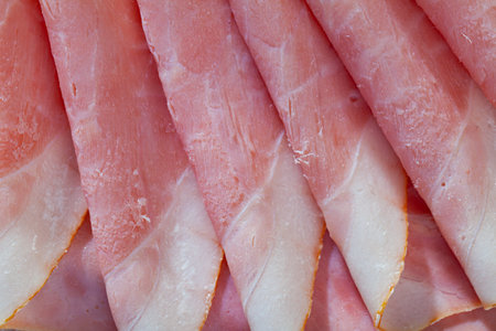 Closeup of sliced tasty ham on wooden cutting board