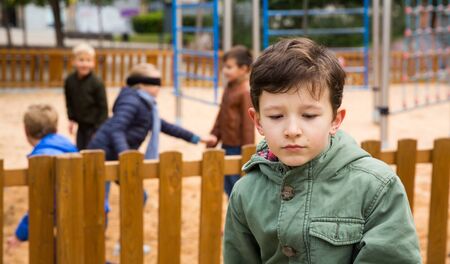Portrait of offended upset boy not playing with friends after quarrel on playgroundの写真素材