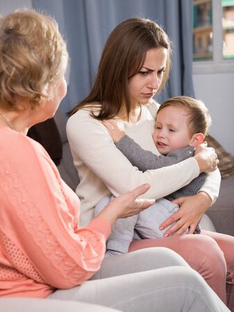 Adult female with her mother are having disagreements for parenting child at home.の写真素材