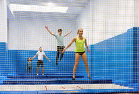View of yellow safety net in trampoline sports center with blurred young people training on backgroundの写真素材