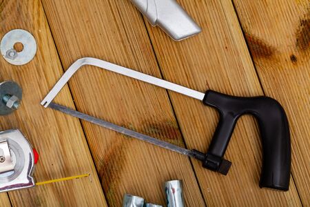 Hacksaw for construction work and melallic tools on wooden surfaceの写真素材