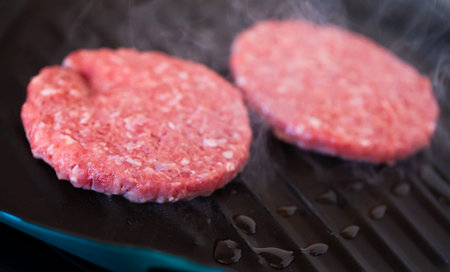 Cooking, barbecue and fast food concept â closeup of burger meat cutlets roasting on brazier grillの写真素材