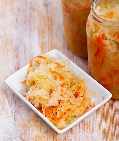 Vegetarian appetizer of sour shredded cabbage in plate on wooden background. Homemade picklesの写真素材