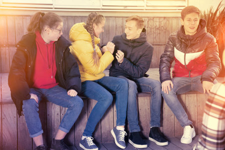 Four cheerful teenage friends having fun while spending time together outdoors on warm spring day
