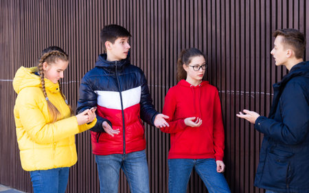 Portrait of four teenage friends chatting outdoors in town