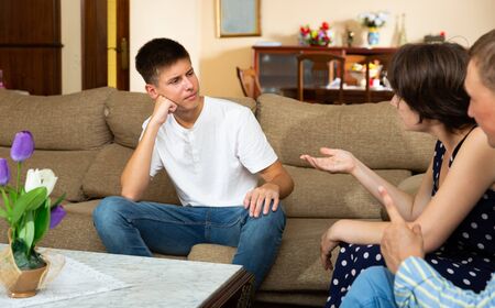 Angry parents quarrelling with his upset teenage son at home interiorの写真素材