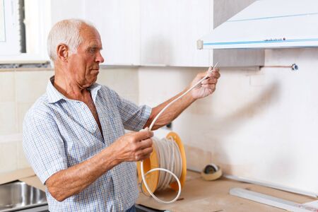 Skillful older man engaged in renovation work indoorsの写真素材