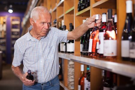 Adult man visiting winehouse in search of bottle of good wineの写真素材