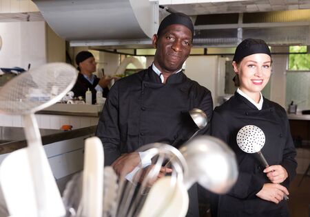 Portrait of two smiling confident chefs posing together in modern professional kitchenの写真素材