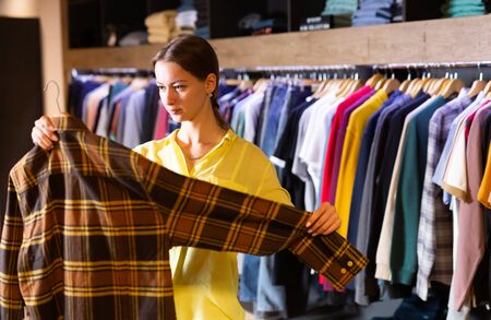 Satisfied woman chooses fashionable checkered shirt in the fashion storeの写真素材