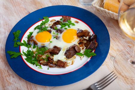 Fried eggs with saffron milk cap mushrooms on bright plateの写真素材