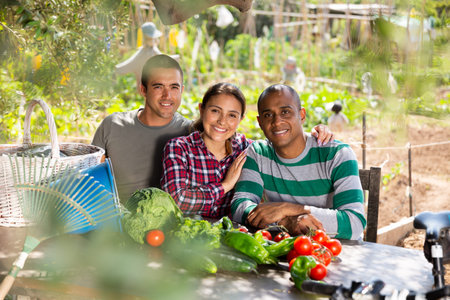 Happy male and female professional gardeners  after harvesting of vegetables in garden outdoor