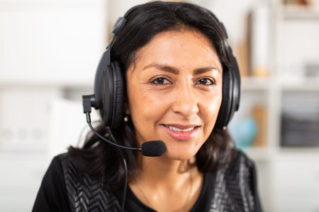 Portrait of smiling Peruvian woman helpline operator with headphones during work in call center