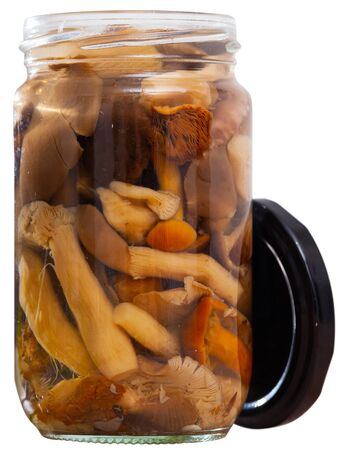 Mix of chopped marinated forest mushrooms in glass jar, homemade preserves. Isolated over white backgroundの写真素材
