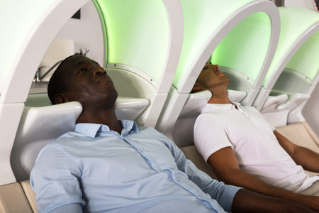 Two men sitting in chairs waiting for hair wash in modern hair salonの写真素材
