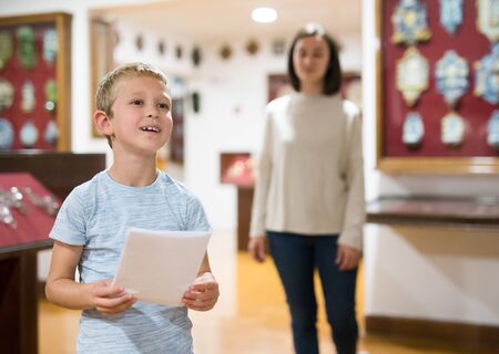 Portrait of boy looking at exposition in historical museum, woman is behindの写真素材