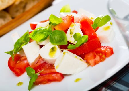 Caprese salad with fresh tomatoes, mozzarella cheese and basilic herb, dish of Italian cuisineの写真素材
