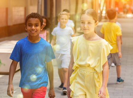 Positive little mexican boy  and his friend girl walking together on the streetの写真素材