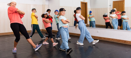 Group of children in casual clothes training hip-hop in class, learning modern dance movements